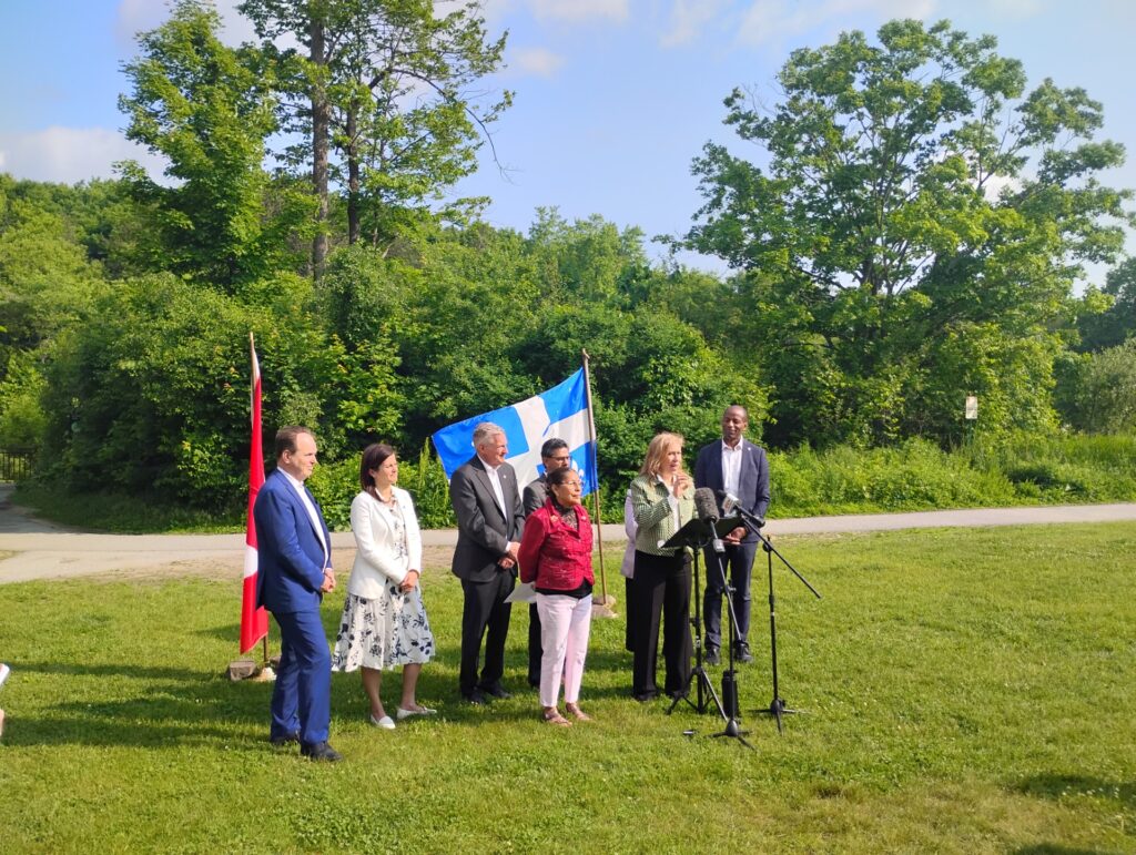 Senator Rosa Galvez and MP Sophie Chatel stand before a scenic backdrop of Gatineau Park as they introduce Bill S-229, a legislative initiative to strengthen protections for the park's ecological integrity